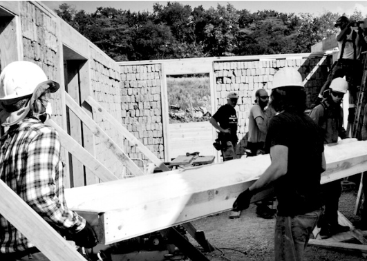 Men in hard hats carry a beam