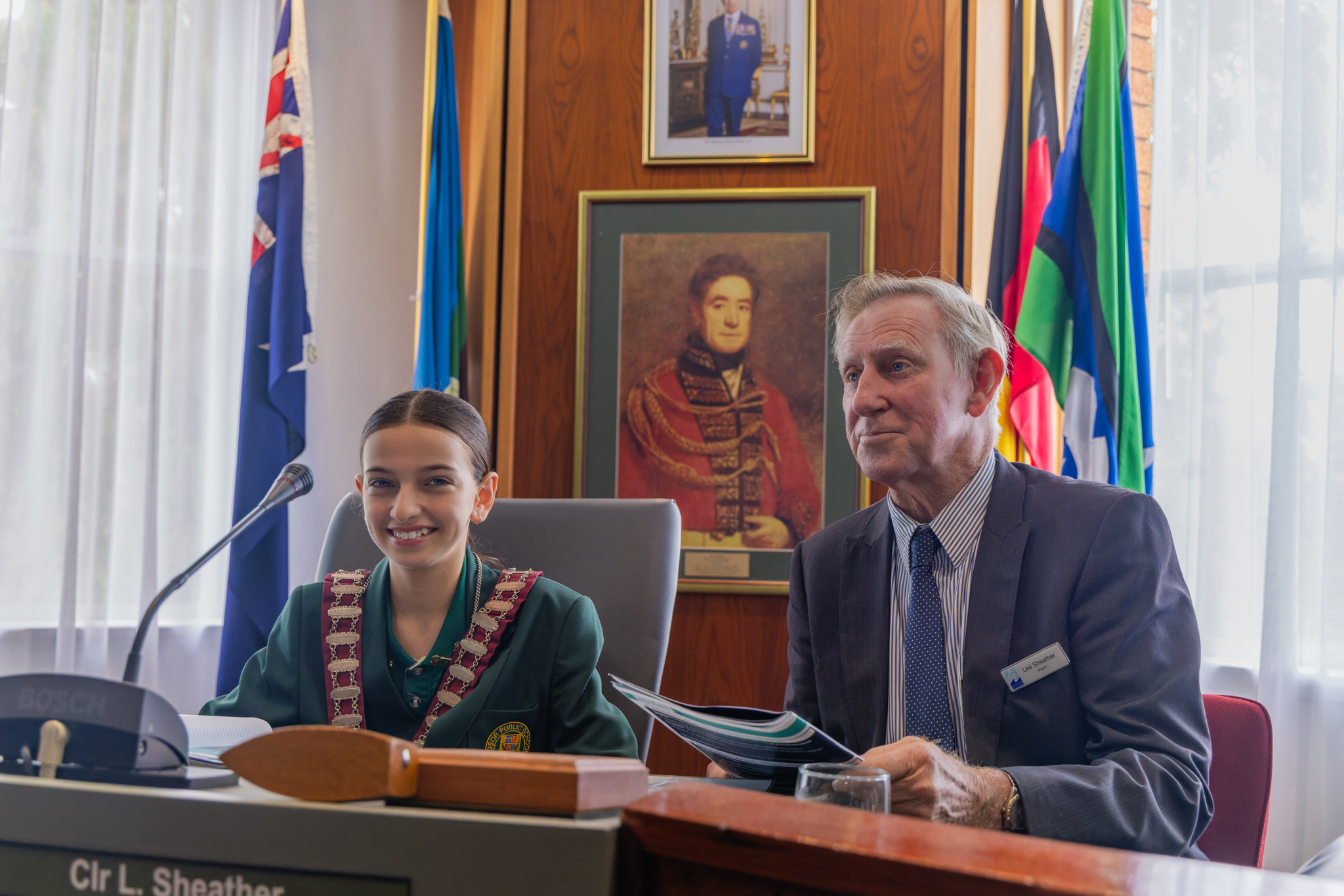 A student role plays the Mayor beside the Mayor at Council.