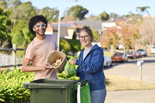 An image of a couple placing food items in a FOGO bin